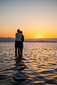 Hugging couple enjoying sunset at Trabucador beach, Ebro Delta, Tarragona, Spain\n