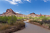 Der schlammige San Rafael River und Assembly Hall Peak. Mexican Mountain Wilderness Study Area am San Rafael Swell in Utah. Rechts ist der schlanke Bottleneck Peak zu sehen. Entlang des Flusses wachsen Cottonwood-Bäume.