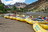 A female river guide walking on white water rafts tied up on shore in Desolation Canyon, Utah.\n