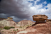 Storm clouds over eroded sandstone formations & colorful bentonite clay hills in the Caineville Desert near Hanksville, Utah.\n