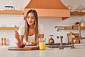 Smiling woman enjoying healthy breakfast in kitchen\n