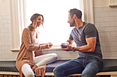 Smiling couple relaxing by window at home\n