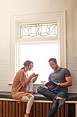 Smiling couple relaxing by window at home\n