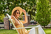 Frau mit Strohhut und Sonnenbrille entspannt im Park