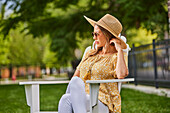 Frau mit Strohhut und Sonnenbrille entspannt im Park