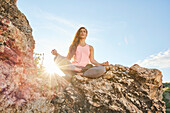 Mid adult woman meditating in mountains\n