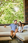 Mid adult couple relaxing on sofa on patio\n