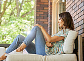 Mittlere erwachsene Frau entspannt auf dem Sofa auf der Terrasse