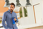 Mittlerer erwachsener Mann in der Küche stehend mit Wasserflasche