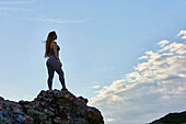 Young woman standing on top of rock while hiking\n