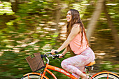 Smiling young woman riding bicycle in park\n