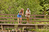 Mutter und erwachsene Tochter stehen auf einer Brücke