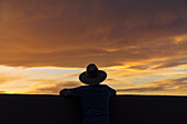 USA, New Mexico, Santa Fe, Silhouette of man in hat looking at sunset\n