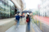 Blurred image of people walking on city street\n