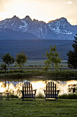 USA, Idaho, Stanley, Scenic view of Sawtooth Mountains with pond at sunset\n