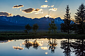 USA, Idaho, Stanley, Scenic view of Sawtooth Mountains with pond at sunset\n