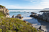 South Africa, Hermanus, Rocky coastline with Atlantic Ocean in Voelklip Beach on sunny day\n