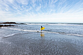 South Africa, Hermanus, Boy (10-11) entering Atlantic Ocean with body board in Voelklip Beach\n