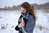 Porträt einer frierenden Frau auf einer verschneiten Wiese