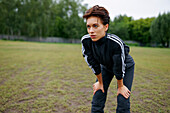 Portrait of young woman standing with hands on knees during sports training\n