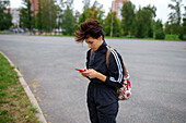 Young woman using smart phone in city street\n