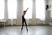 Ballerina standing on tiptoes with raised arms \n