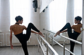 Ballerina stretching legs in dance studio \n