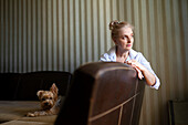 Woman sitting on sofa with Yorkshire terrier at home \n