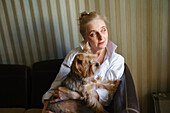 Woman sitting on sofa and holding Yorkshire terrier\n