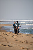 Two young men riding their bikes on the sand during Quiksilver Festival celebrated in Capbreton, Hossegor and Seignosse, with 20 of the best surfers in the world hand-picked by Jeremy Flores to compete in south west of France.\n