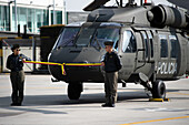 Zwei Piloten halten ein Band der kolumbianischen Flagge vor einem UH60 Black Hawk während einer Veranstaltung auf der CATAM - Airbase in Bogota, wo die Botschaft der Vereinigten Staaten von Amerika in Kolumbien am 27. September 2023 drei Lockheed Martin UH60 Black Hawks zur Verbesserung der Antidrogenoperationen übergab.
