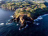Aerial view of the coasts and cliffs of the island of Sao Miguel over the lighthouse of Farolim dos Fenais da Ajuda, Azores Islands, Portugal, Atlantic, Europe\n