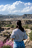 Junge Frau mit Blick auf die Wüste von Tabernas an einem sonnigen Tag, Almeria, Andalusien, Spanien, Europa