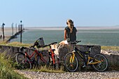 France, Somme, Somme Bay, Saint-Valery-sur-Somme, Cape Hornu, Young woman in mountain bike in front of the channel of the Somme\n