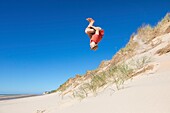 France, Pas de Calais, Wissant, young man doing an acrobatics in the dunes (Cape Blanc-Nez in the background)\n