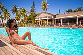 France, Caribbean, Lesser Antilles, Guadeloupe, Grande-Terre, Le Gosier, a woman relaxes by the pool of the hotel Creole Beach\n