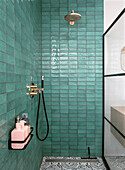 Green tiled shower with black tap and pink soap dispenser