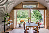 Dining area in a tiny house with arched metal roof and light-colored wooden floor