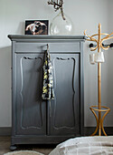 Grey wardrobe with glass vase, next to it a coat rack