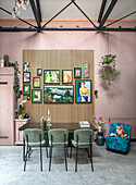 Dining area with wooden slatted wall, pictures, black table and upholstered chairs