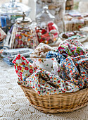 Fabrics with floral patterns in a basket on a crocheted tablecloth