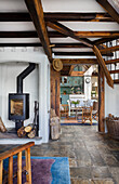 Open-plan living area with wood-burning stove, rustic wooden beams and stone floor