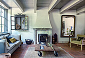 Living room with open fireplace, wooden beamed ceiling and rustic coffee table on castors