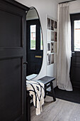 Entrance area with oval mirror and dark wooden cabinet