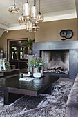 Living room with modern fireplace, glass pendant lights and grey velvet sofa