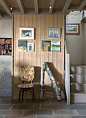 Stuhl und Ast vor Holzwand mit Bildern