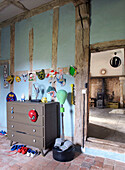 Chest of drawers in rustic children's room with blue wall and wooden beams