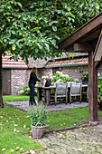 Woman stroking cat on terrace with wooden furniture and bowl of lavender plants