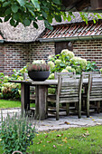 Wooden table with chairs and flower arrangement on garden terrace