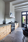 Kitchen with light-coloured walls, black details and wooden fronts